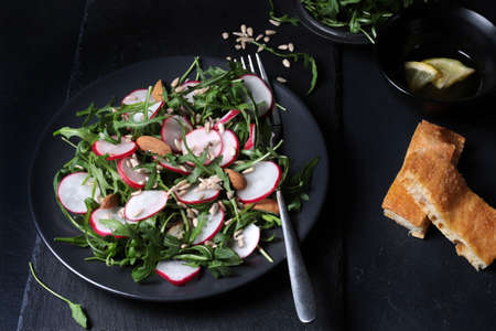 Fresh salad with rockets, radishes and almond on dark background. Healthy food.の写真素材