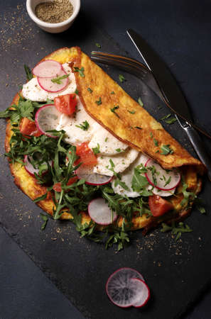 Fresh omelet with cheese and vegetables on dark background. Top view.の写真素材