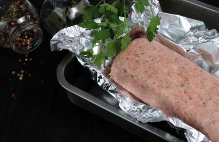 Raw meatloaf on a tray on dark background. Top view. Copy space.の写真素材