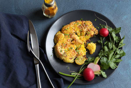Cauliflower steak with herbs and spices on dish on dark background. Close up view.の写真素材
