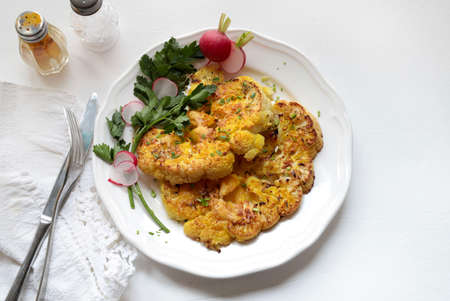 Cauliflower steak with herbs and spices on dish isolated on white background. Close up view.の写真素材