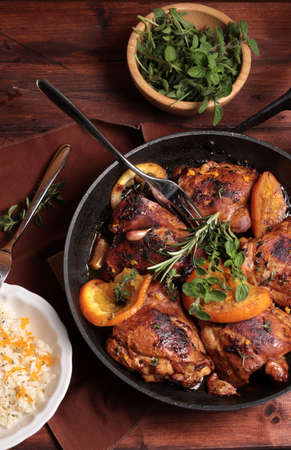 Roasted chicken with oranges and herbs in a pan on wooden background. Directly above.の写真素材