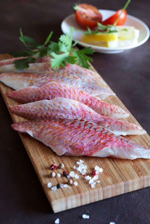 Fresh gurnard fillet with lemon on wooden cutter board. Directly above.の写真素材