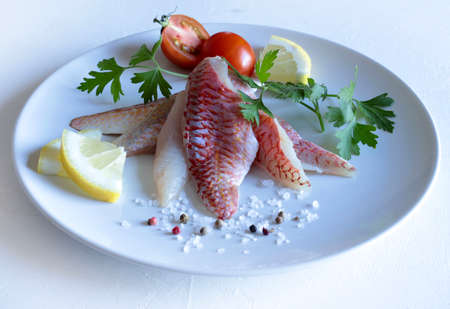 Fresh gurnard fillet with lemon on white plate.の写真素材