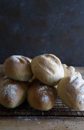 Concept of home baking. Homemade freshly baked bread and buns on wooden table. Top view, copy space.