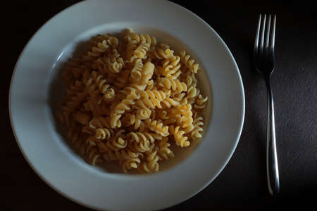 Raw fusilli pasta in on dark background. Directly above.