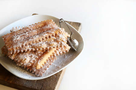 Homemade traditional Italian carnival sweets: chiacchiere on white background. Copy space. Directly...