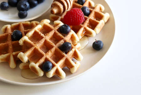 Belgian waffles with fresh fruit and honey on a plate isolated on white background. Directly above.
