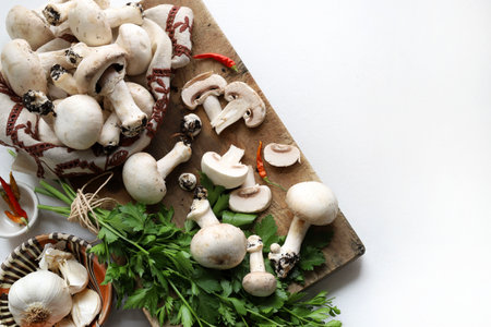Fresh champignon mushrooms and ingredients for cooking on white background. Cooking organic mushroom. Directly above. Copy space.の写真素材