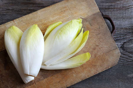 Group of raw endives on a wooden background.