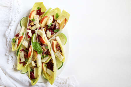 Endive leaves stuffed with cheese, walnuts, apple, radishes, honey and lime sprinkled with fresh basil leaves. Directly above.の写真素材