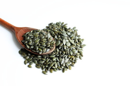 pumpkin seeds in wooden spoon isolated on a white background.の写真素材