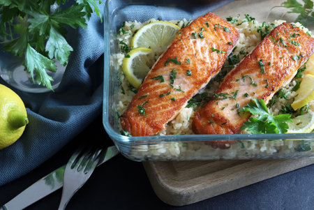 Roasted salmon with rice, lemon and parsley on wooden boardの写真素材