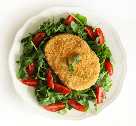 Soy meat cutlet with fresh rocket, slice tomatoes in a white plate, white background. Healthy, vegan...