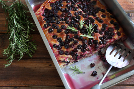 Traditional tuscan dessert. Homemade "Schiacciata all'uva", typical Tuscan sweet focaccia with black grapes and rosemary on a wooden background. Directly above.の写真素材