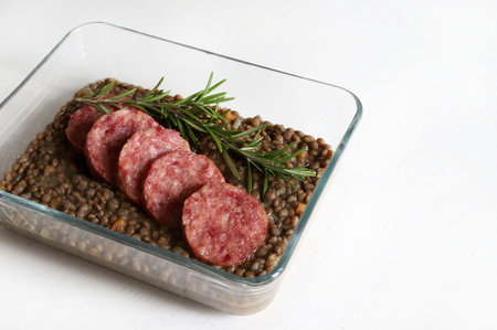 Italian Festive New Year meal. Cotechino with lentils and decorated with fresh rosemary on a white wooden table. Christmas holiday. Directly above.の写真素材
