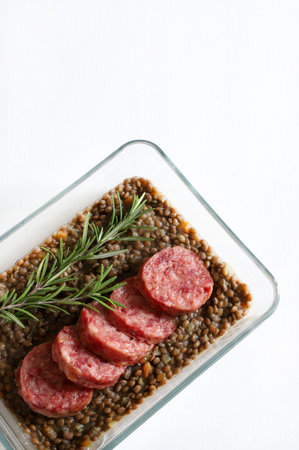 Italian Festive New Year meal. Cotechino with lentils and decorated with fresh rosemary on a white wooden table. Christmas holiday. Directly above.の写真素材