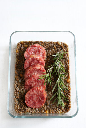 Italian Festive New Year meal. Cotechino with lentils and decorated with fresh rosemary on a white wooden table. Christmas holiday. Directly above.の写真素材