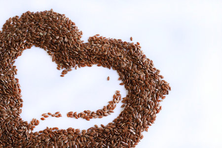 Flax seeds in heart shape on white background with copy space.の写真素材