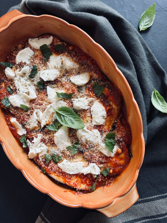 Baked aubergine parmesan. Dish based on aubergines, tomato sauce, fresh basil leaves, parmesan and mozzarella. Italian food. Directly above.の写真素材