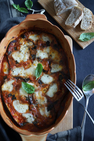Baked aubergine parmesan. Dish based on aubergines, tomato sauce, fresh basil leaves, parmesan and mozzarella. Italian food. Directly above.