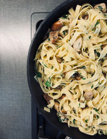 Italian food. Tagliatelle with porcini mushrooms and parsley in a pan on dark background. Homemade autumn dish. Overhead view.の写真素材