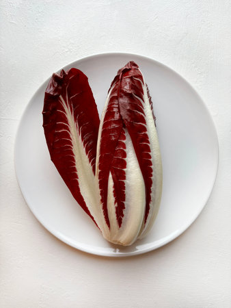 Red radicchio, a Treviso variety on a plate. It's a chicory with long, deep red leaves and white veins. Healthy and vegetarian food. Italian cuisine.の写真素材