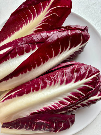 Red radicchio, a Treviso variety on a plate. It's a chicory with long, deep red leaves and white...