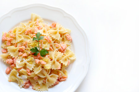 Plate of farfalle pasta with smoked salmon garnished with fresh parsley and lemon isolated on white background. Italian food. Overhead view.の写真素材