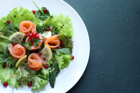 Smoked salmon salad with lettuce, rocket garnished with red currants, lemon slices, pepper and fresh parsley. Fresh and healthy dish. Green background.の写真素材