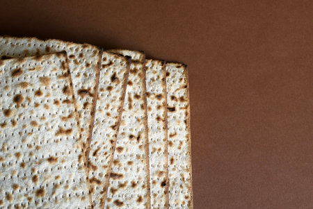 A pile of matzah isolated on a brown background. Matzah unleavened bread made only with flour and water. Jewish holiday of Pesach (Passover) concept.の写真素材