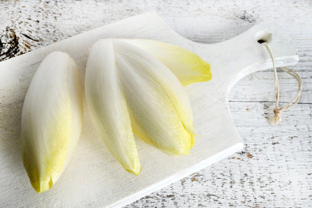 Fresh raw Belgian endives (chicory) isolated on a wooden background. Healthy and vegetarian food....