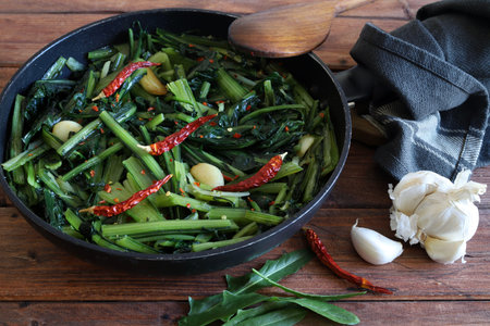 Italian sautÃ©ed chicory greens with garlic and hot peppers in a pan on rustic background. Italian...