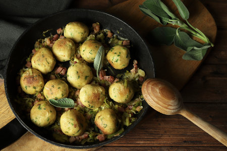 Pan-fried gnocchi or canederli with smoked bacon and leeks, garnished with sage leaves on a rustic...