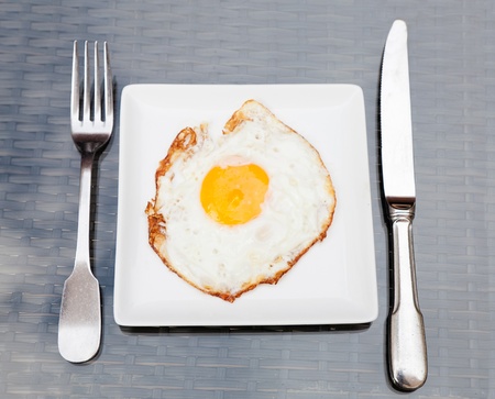 Fried eggs on a plate with place settingの写真素材