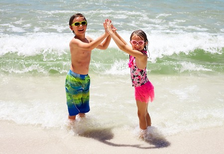 Happy little children holding hands on beachの写真素材