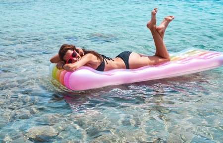 Cheerful young woman resting on lilo in waterの写真素材