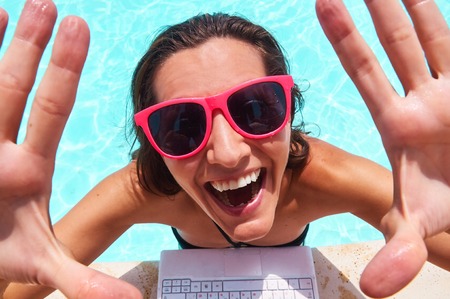 Excited young woman waving hands at poolsideの写真素材
