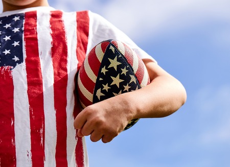 Close-up of little American boy holding rugby ballの写真素材