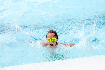 Excited little boy splashing in pool and screamingの写真素材