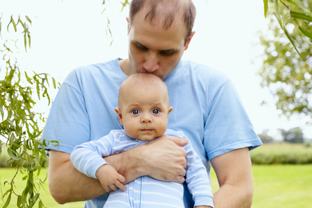 Happy young father kissing his newborn son outdoorの写真素材