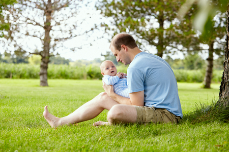 Smiling young man looking at his newborn sonの写真素材