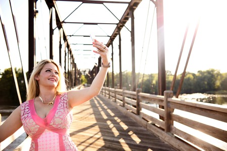 Smiling young woman taking selfie on bridgeの写真素材