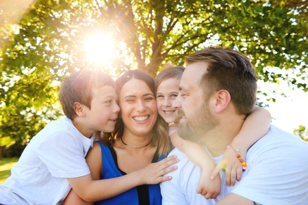 Joyful family sitting together embraced in summerの写真素材