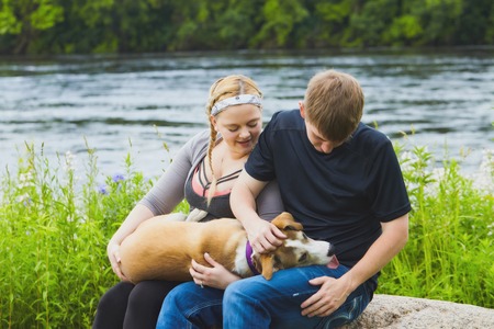 Portrait of smiling young couple patting their dogの写真素材