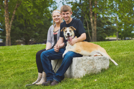 Portrait of happy couple sitting on stone with dogの写真素材