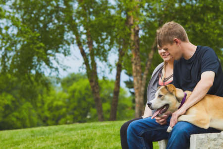 Smiling couple resting on stone with their dogの写真素材