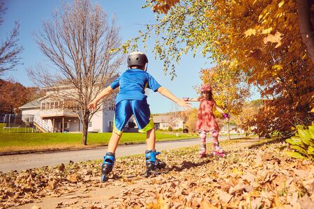 Happy little kids roller skating in autumn parkの写真素材