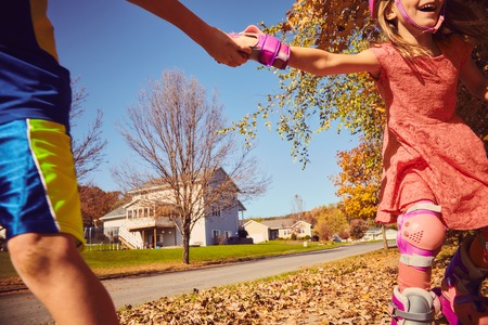 Happy kids holding hands while rollerskatingの写真素材