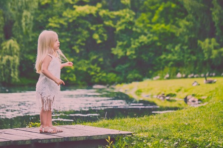 Portrait of serious little girl standing on bridgeの写真素材
